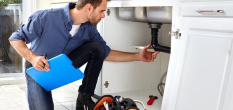 plumber assessing pipes under the sink