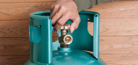 hand turning on blue-green gas cannister